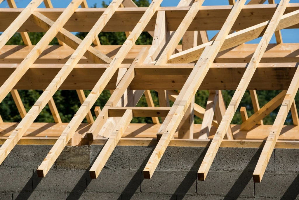 Structure intérieure en bois d'une charpente de toit en construction, montrant les chevrons et les poutres.