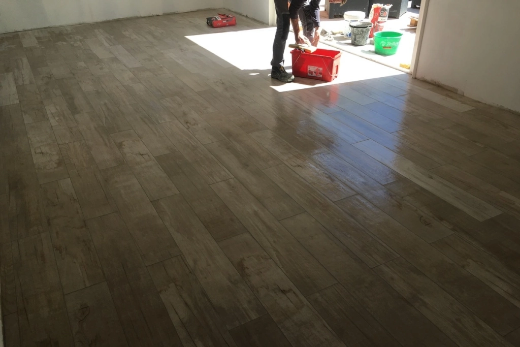 Nettoyage d'un sol en carrelage imitation bois dans une pièce après la pose, lors d'un chantier de construction ou de rénovation