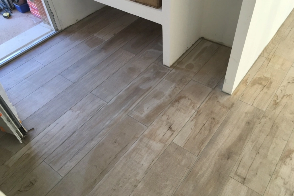 Pose de carrelage imitation bois dans un salon d'une maison en construction ou en rénovation