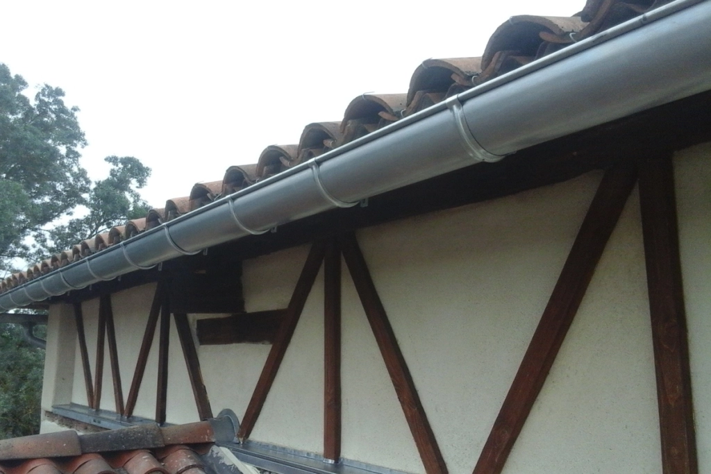 Nouvelle gouttière en zinc installée sur un toit en tuiles d'une maison